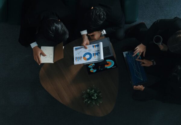 Top down aerial view of professional business man handed out business document to investor while manager placed tablet display financial statistic graph on table and listen presentation. Directorate.